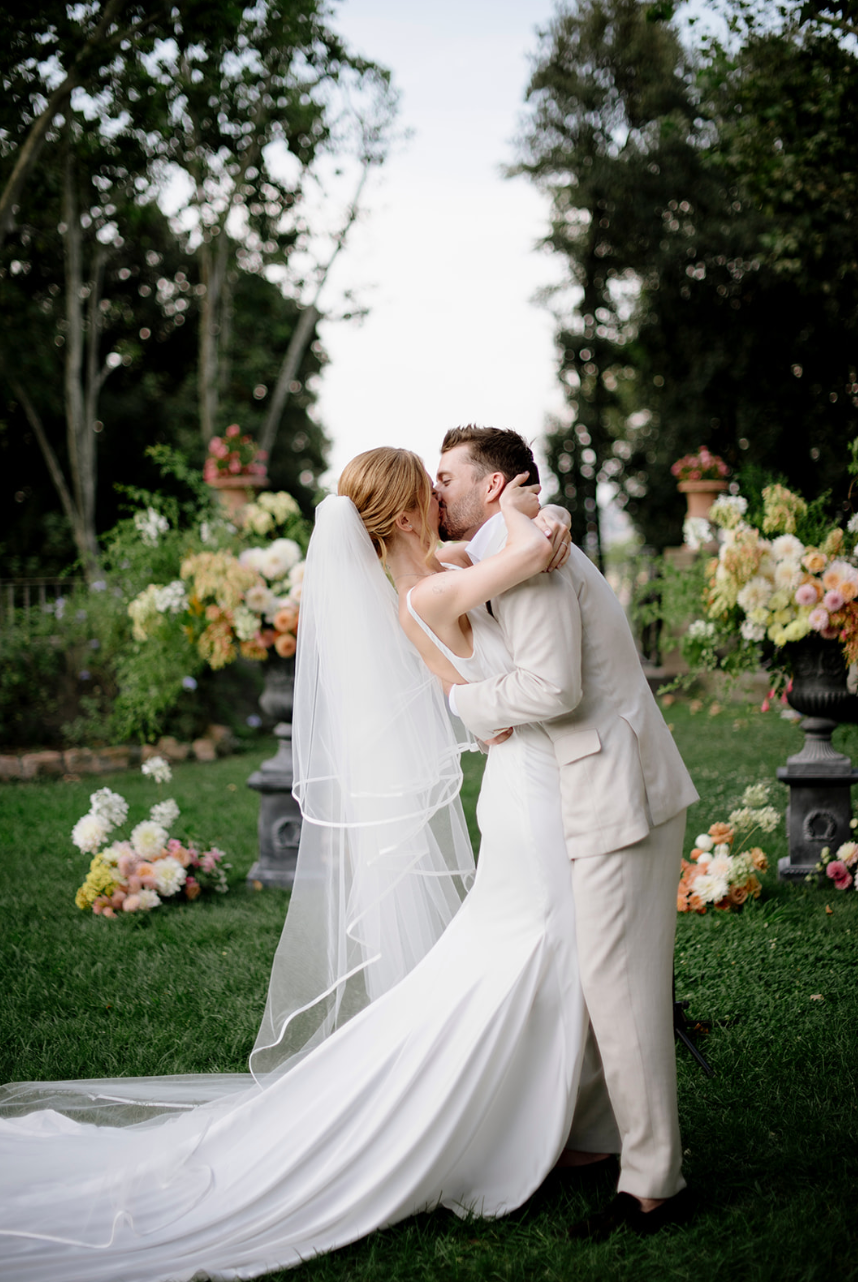 Romantic garden wedding scene with flowing white dress and lush floral arrangements.