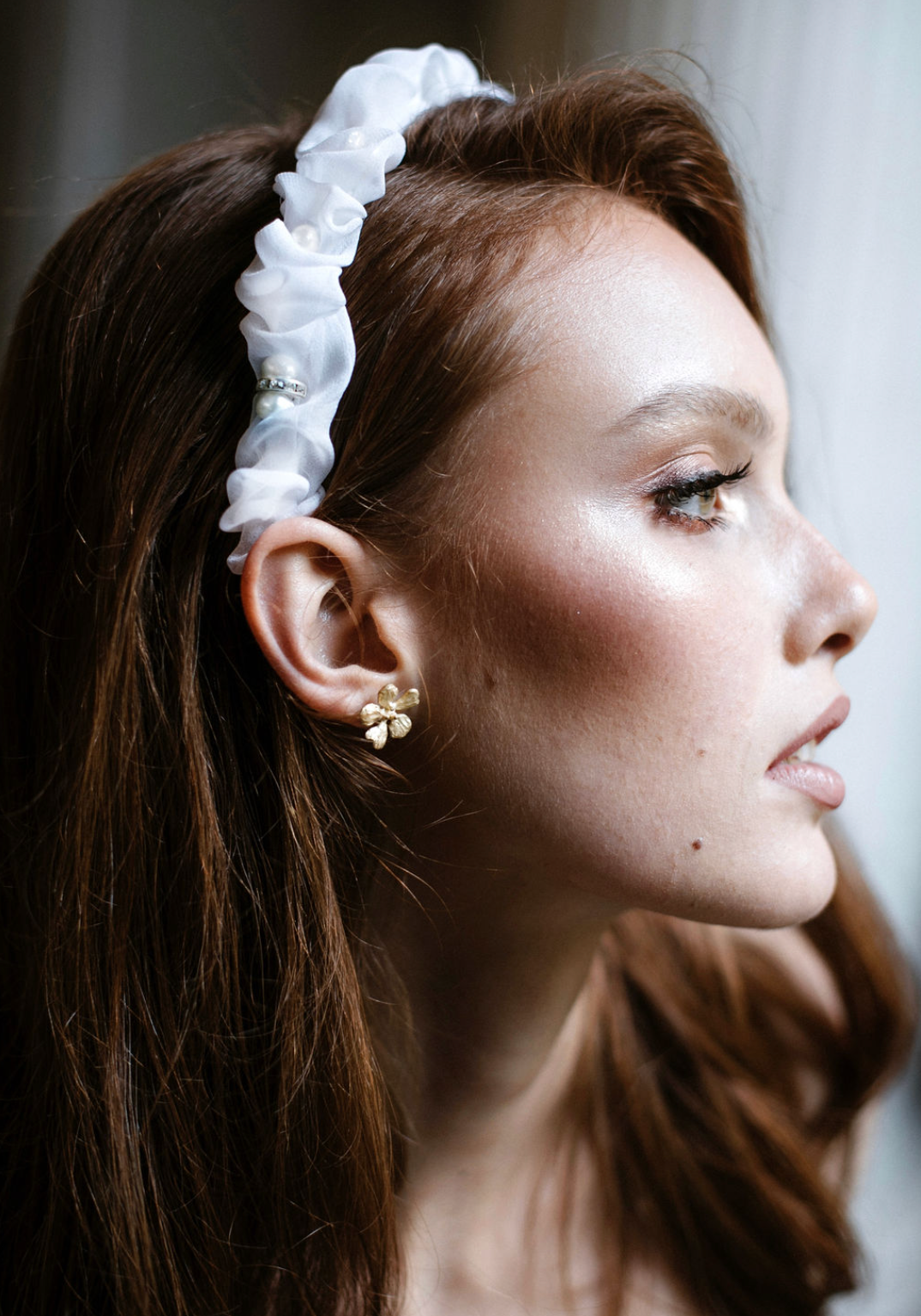 Close-up profile shot showcasing delicate white hair accessory and pearl earring.