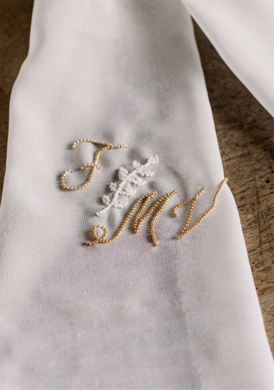 Elegant monogram embroidered in gold and white beading on white fabric.