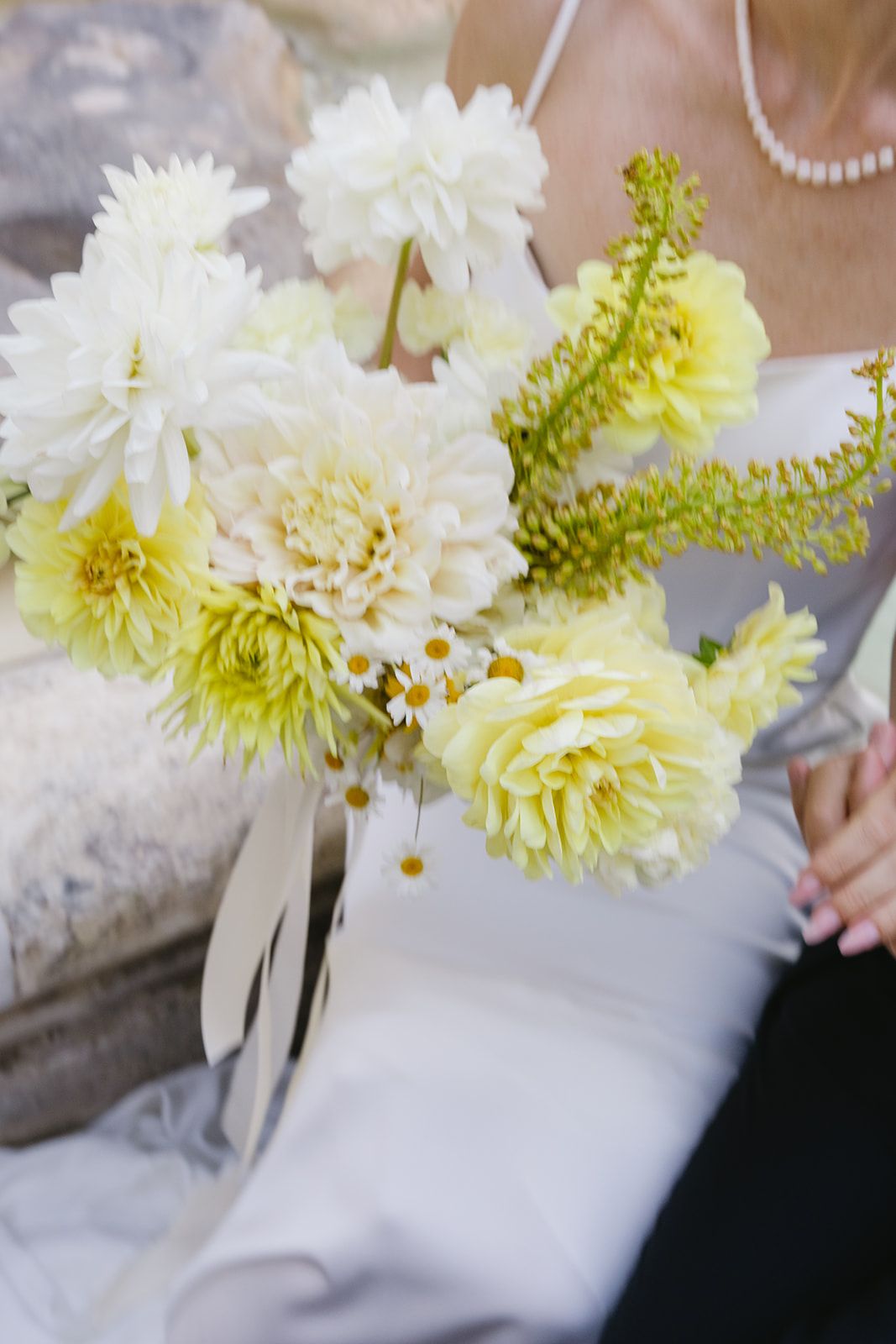 White and yellow chrysanthemum bouquet against soft fabric background.