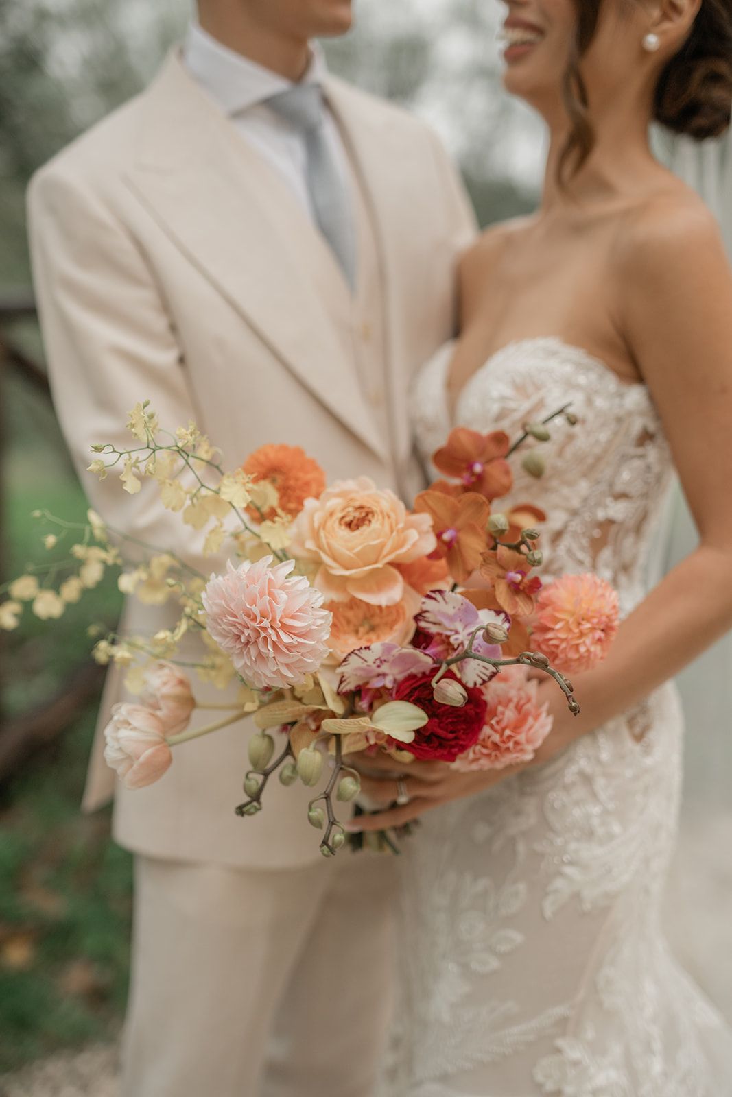 Romantic peach and coral wedding bouquet with dahlias and orchids.