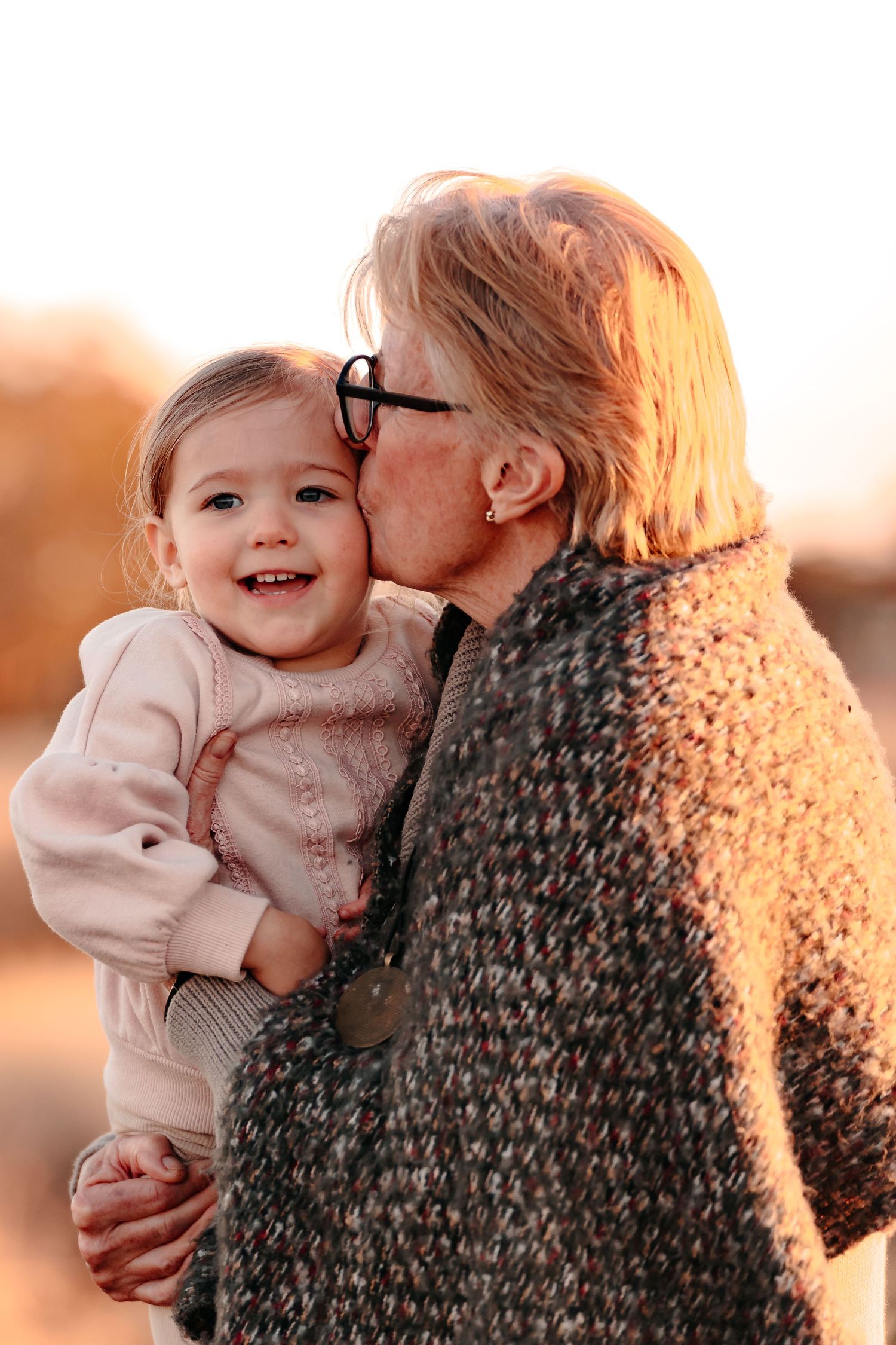 A doting grandmother kissing her beloved granddaughter on the head during a lovely, simple everyday moment
