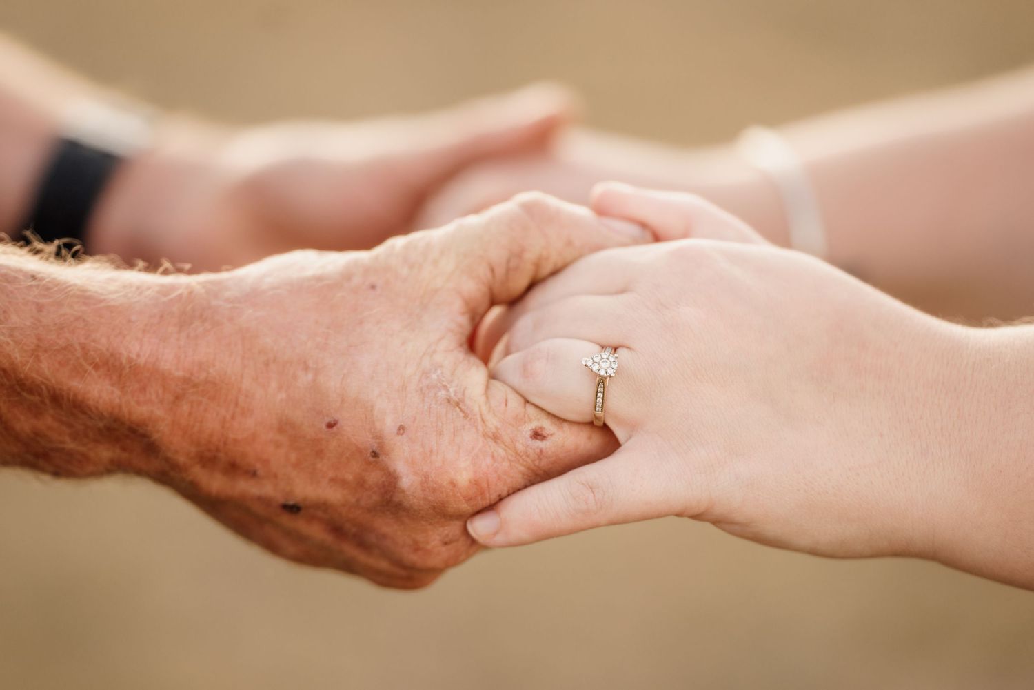 A close up image of 2 peoples' hands. They have just gotten engaged. Tear drop ring is featured.