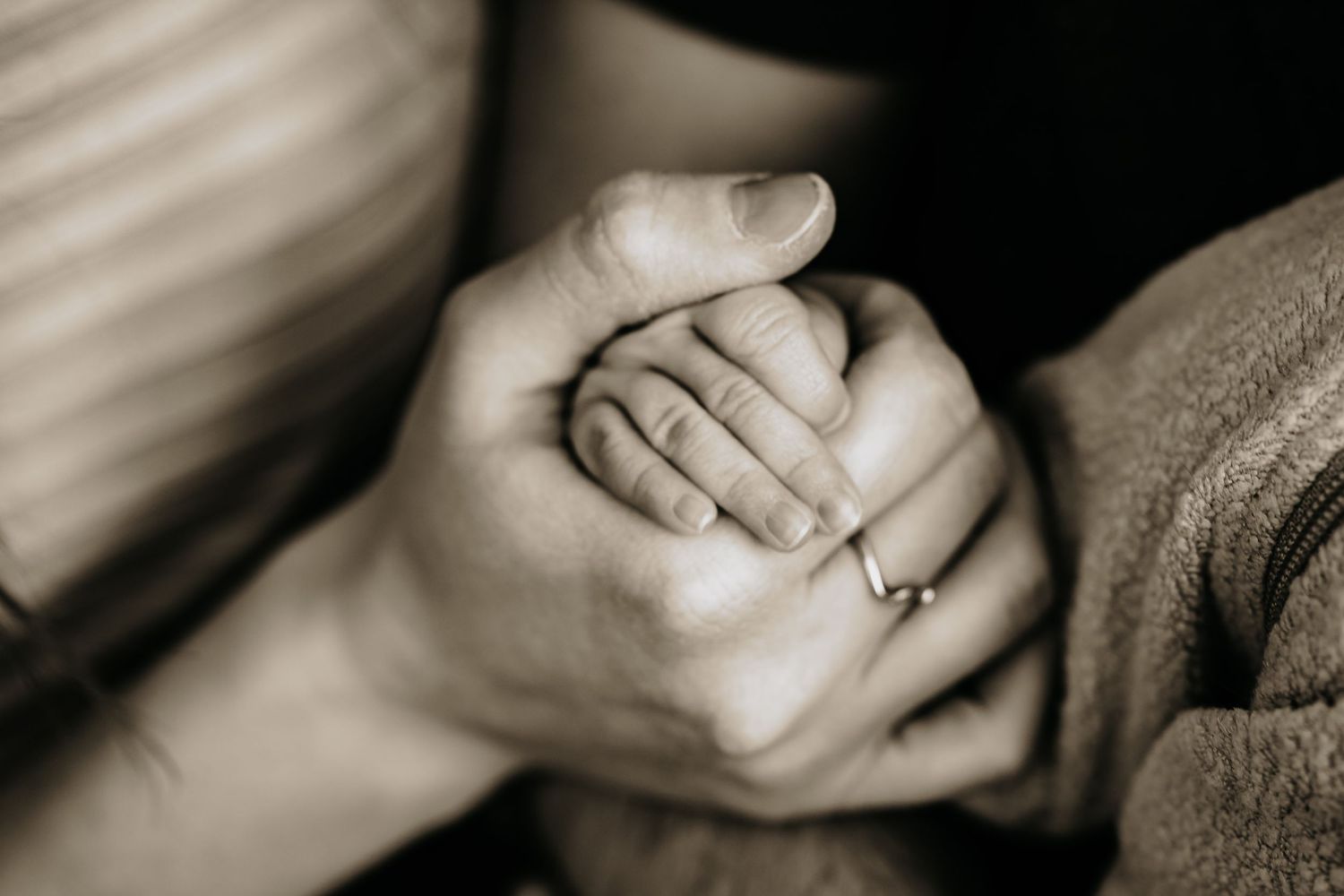 mum holding a newborns tiny little hand. close up details of the fingers in black and white