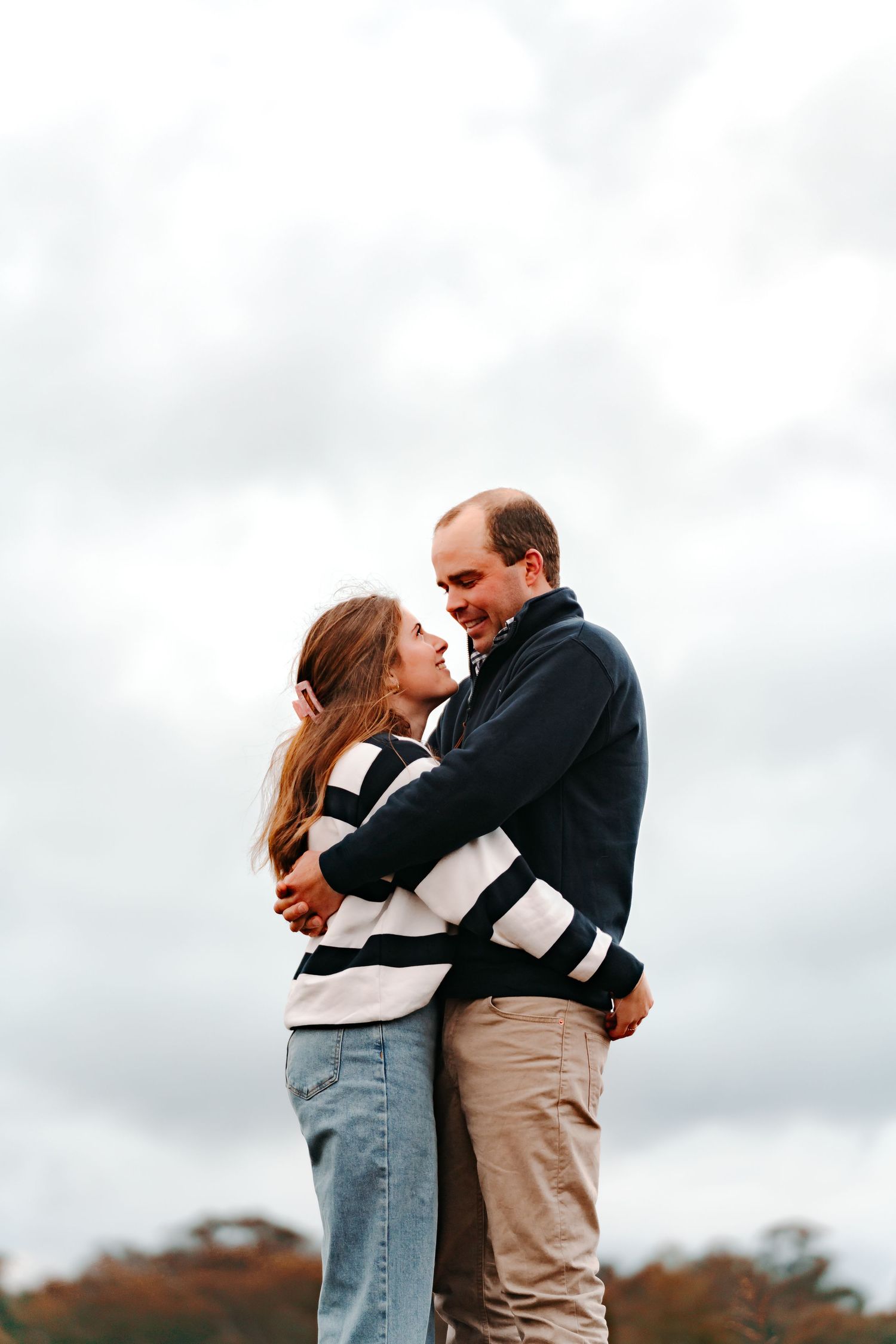 Pictured is a young couple hugging & staring lovingly into each others eyes during an outdoor sunset shoot in Parkes