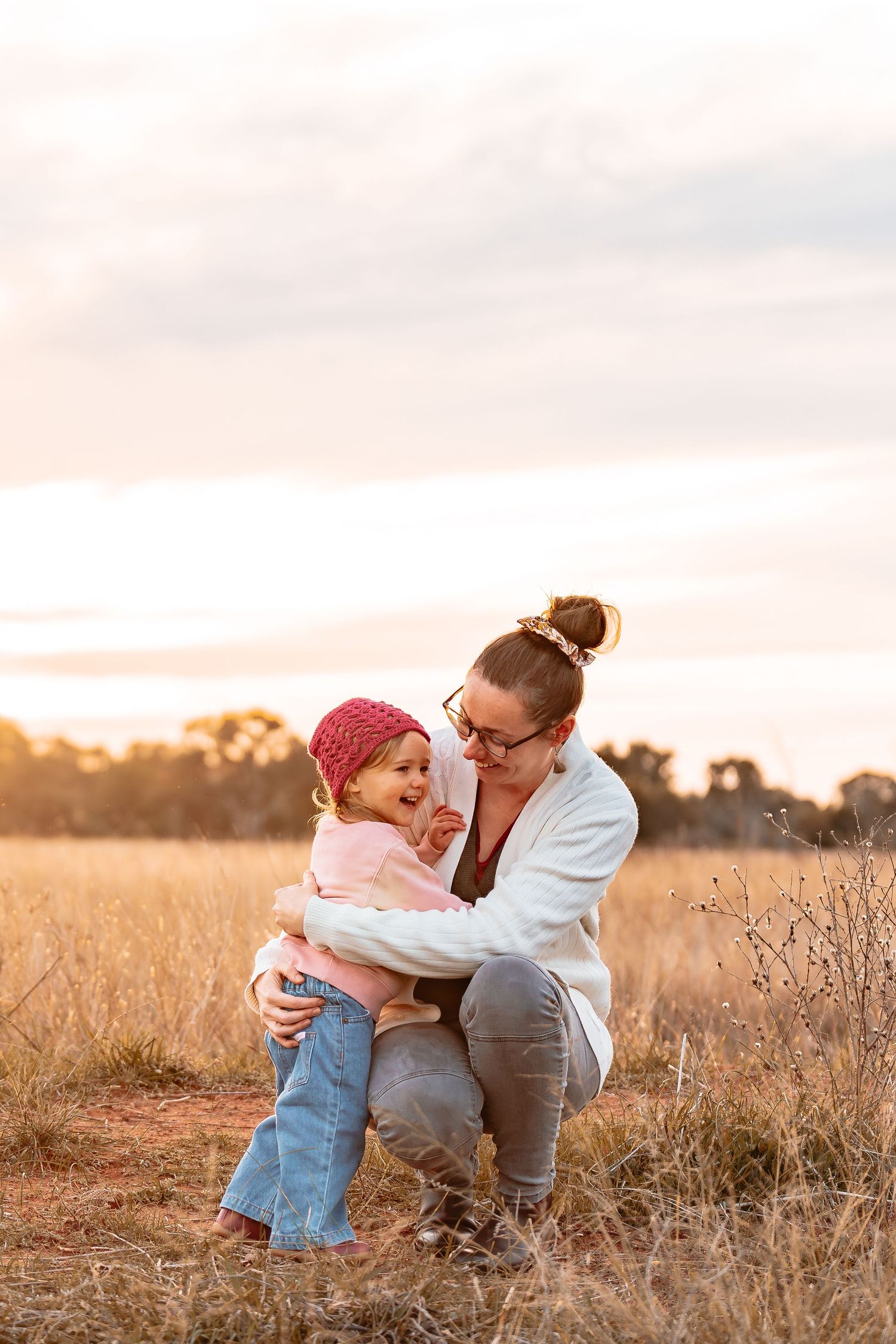 A mother embracing her gorgeous, happy & vibrant 2 year old daughter with a beautiful sunset glow.