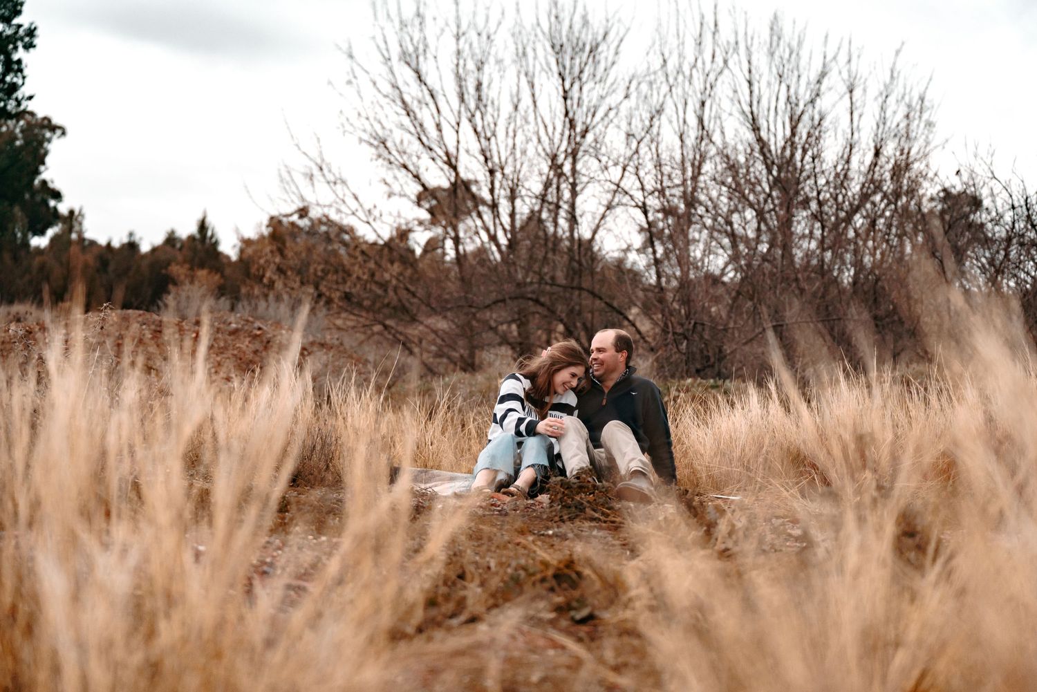 A long distant shot of a couple interacting & laughing together. Not posed & pure connection.