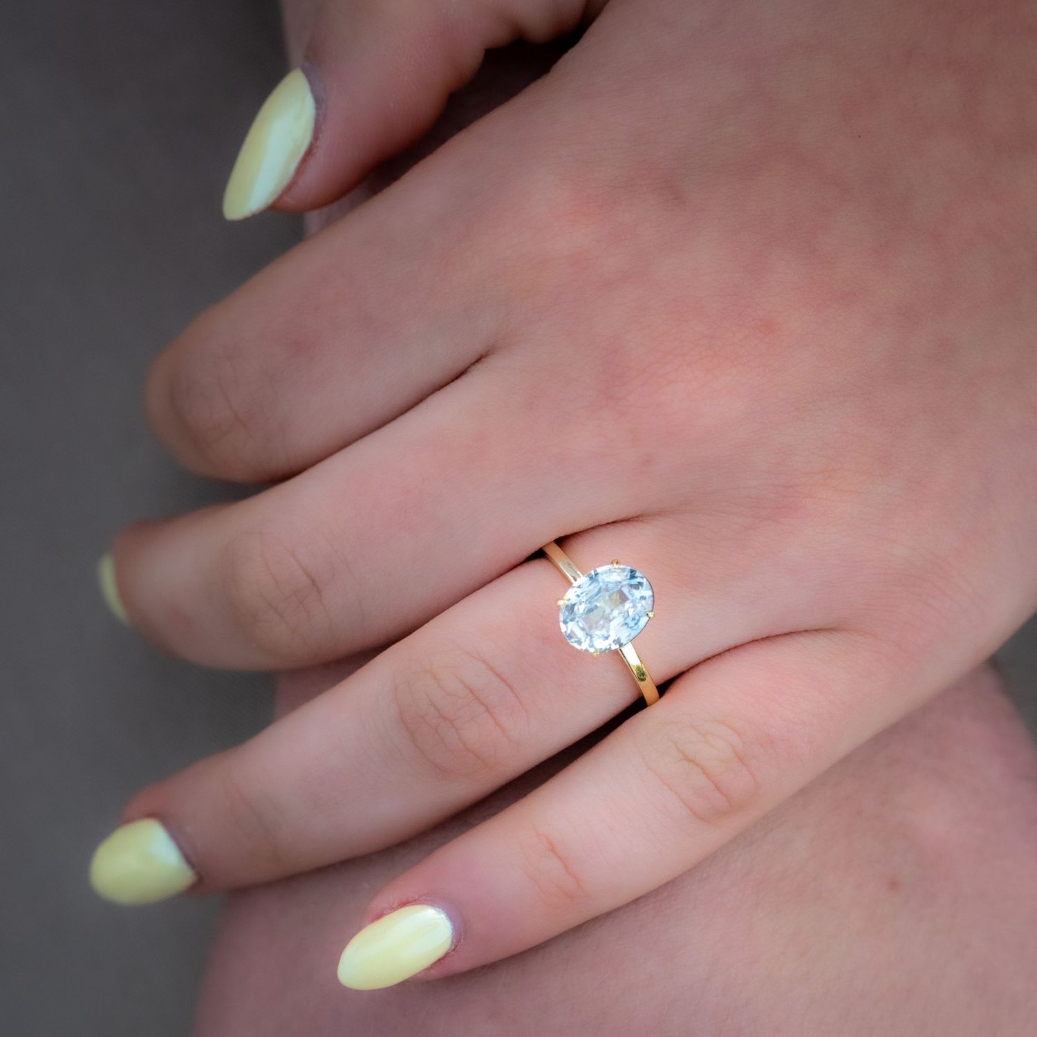 A close-up shot of an engagement ring with a round diamond on a delicate band.