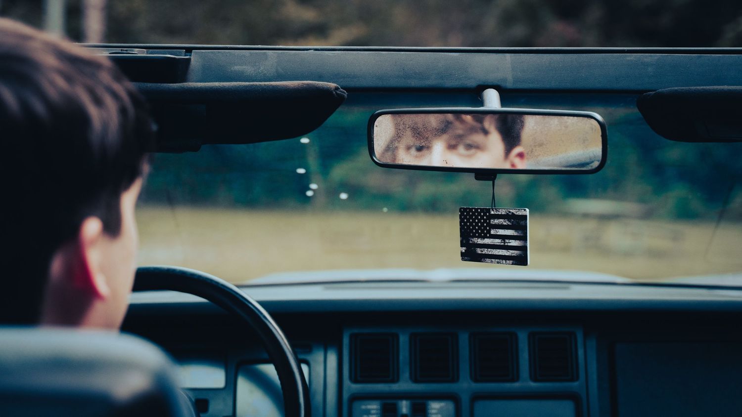 Interior view of car dashboard and rearview mirror during daytime drive. Senior Photo.