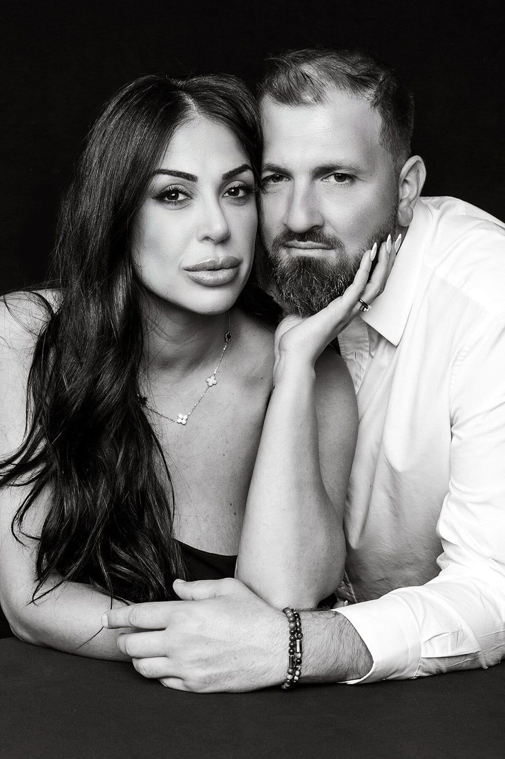 Intimate black and white portrait series of couple in casual white clothing laying close together.