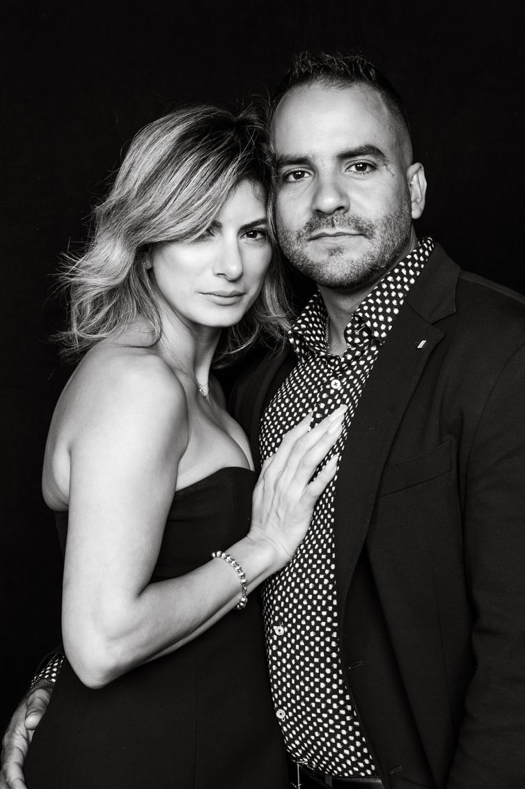 Stylish couple in black attire poses intimately for black and white photo series.