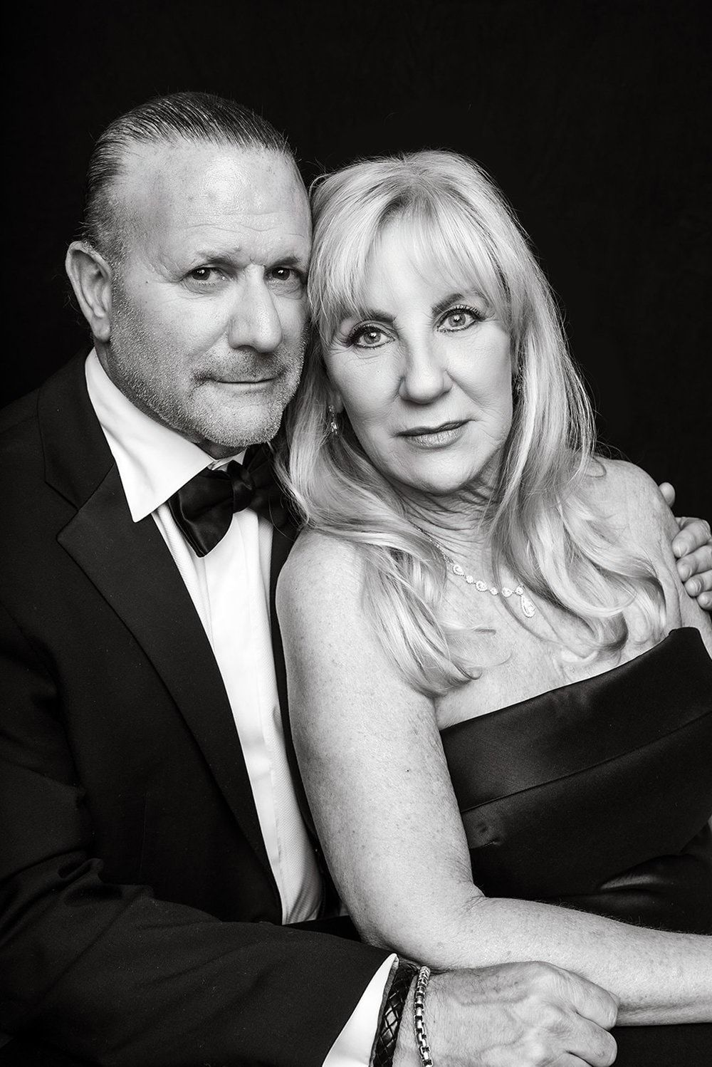 Romantic couple in formal wear share tender moments in black and white studio portraits.