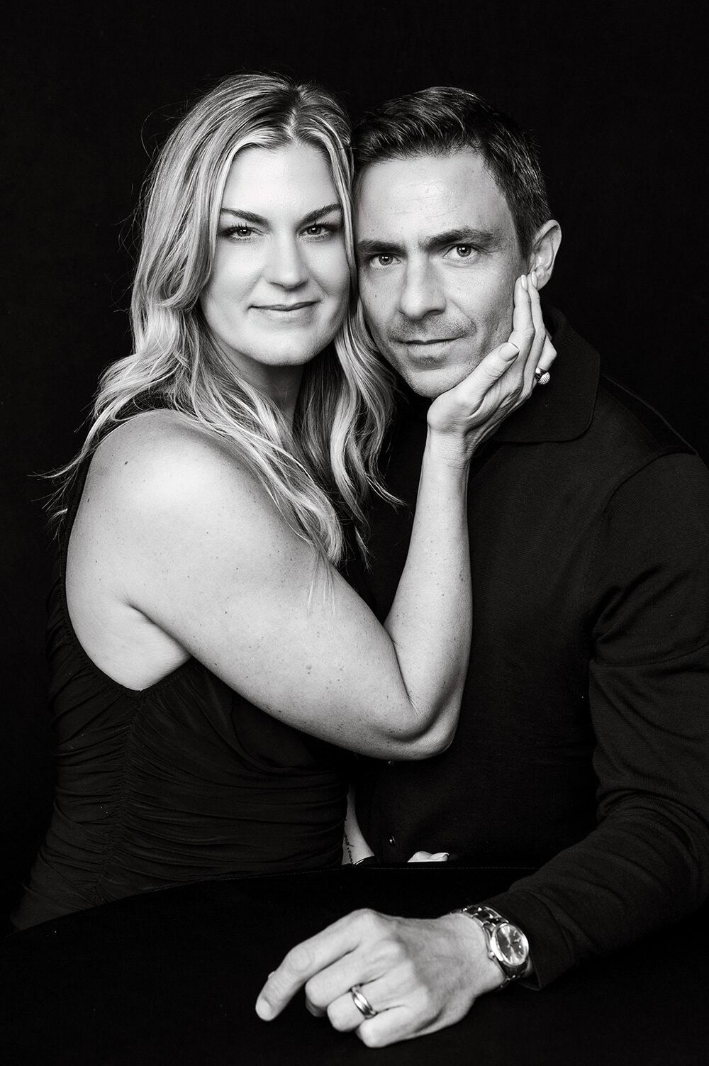 Romantic black and white portrait series showing intimate couple poses against dark background.
