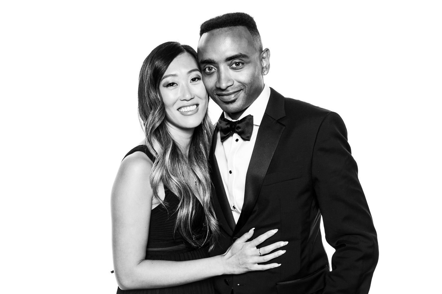 Stylish couple in formal attire share intimate moments in black and white portrait series.