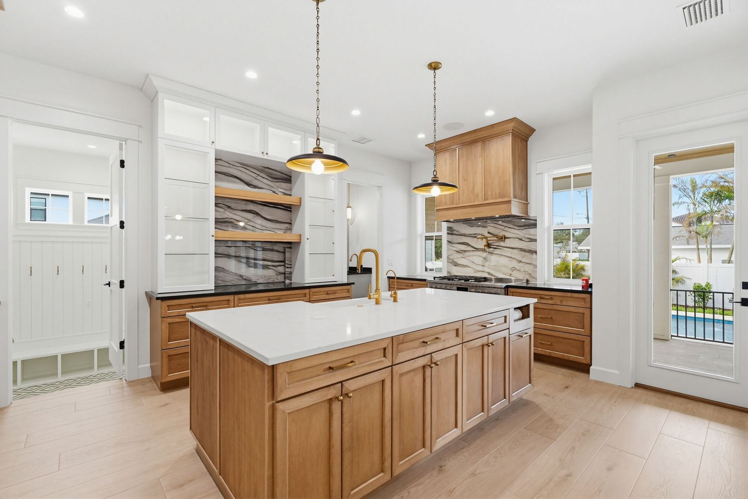 Bright modern kitchen with honey-colored wood cabinets, white countertops, and recessed lighting creates a warm atmosphere.