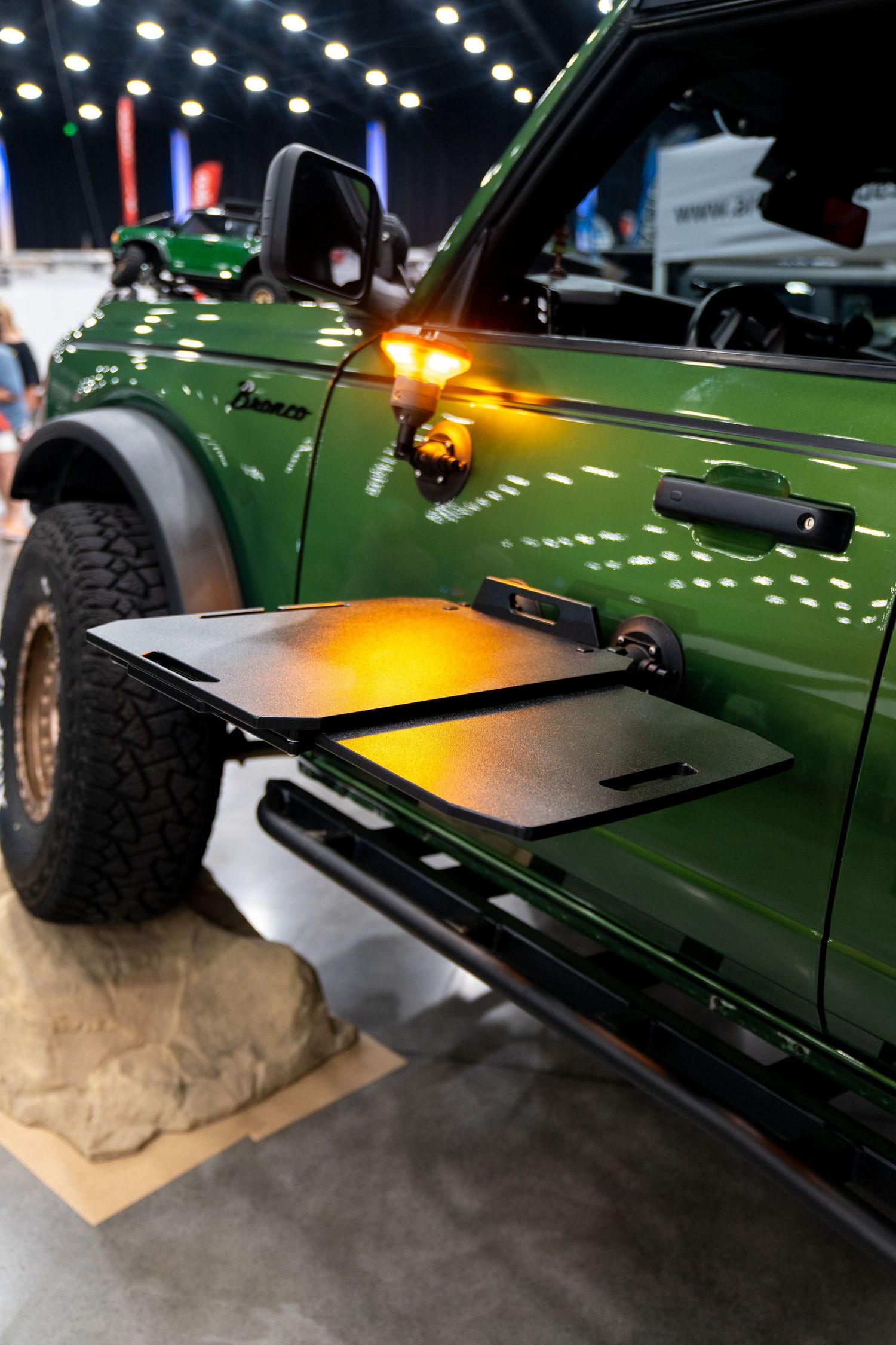 Side view of a green off-road vehicle with amber warning lights mounted on the side panels.