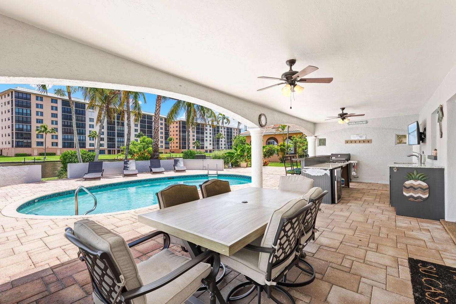 Panoramic view of a patio area with stone pavers and outdoor seating near a swimming pool.