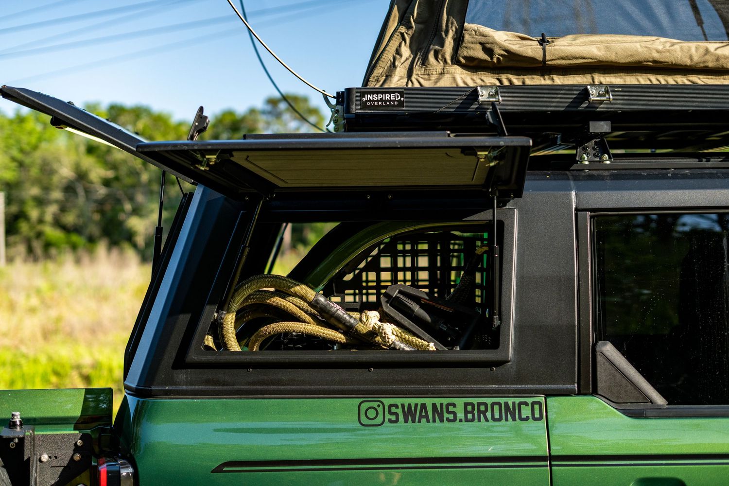 Green rooftop tent installation on adventure vehicle shown in daylight.