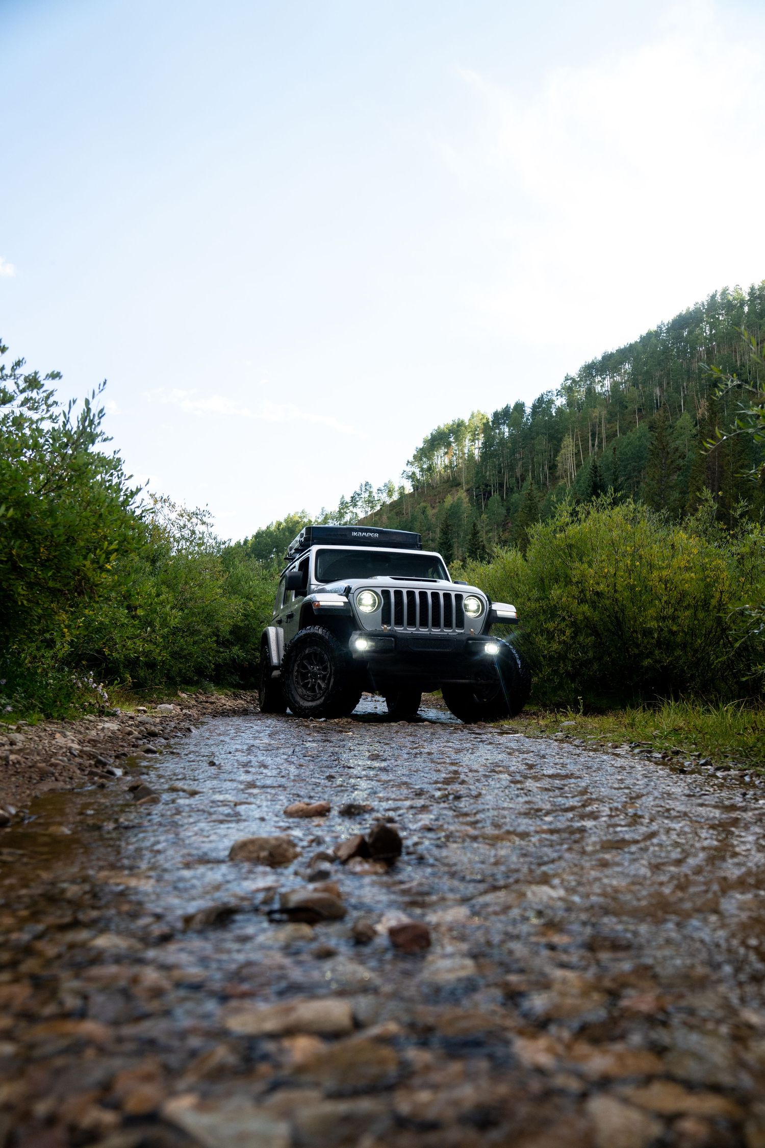 Low-angle view of a white Jeep traversing a rocky mountain trail.