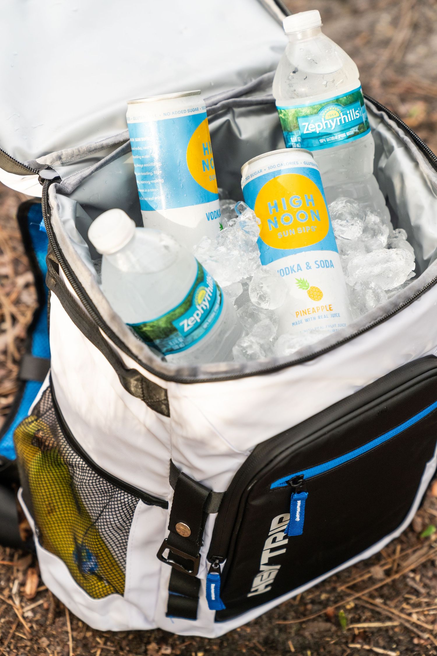 White cooler bag filled with ice and beverages including canned drinks and water bottles.
