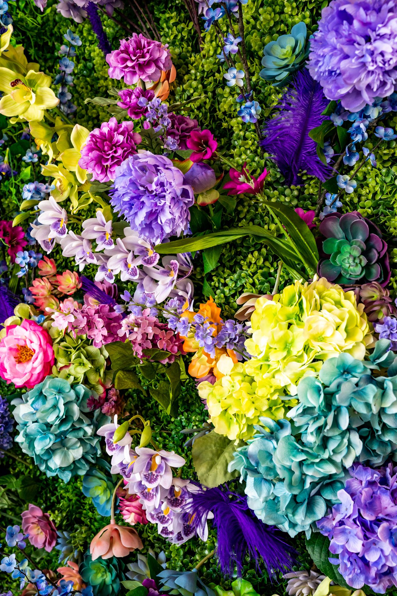 Vibrant floral arrangement featuring purple, yellow, pink and turquoise hydrangeas with delicate greenery accents.