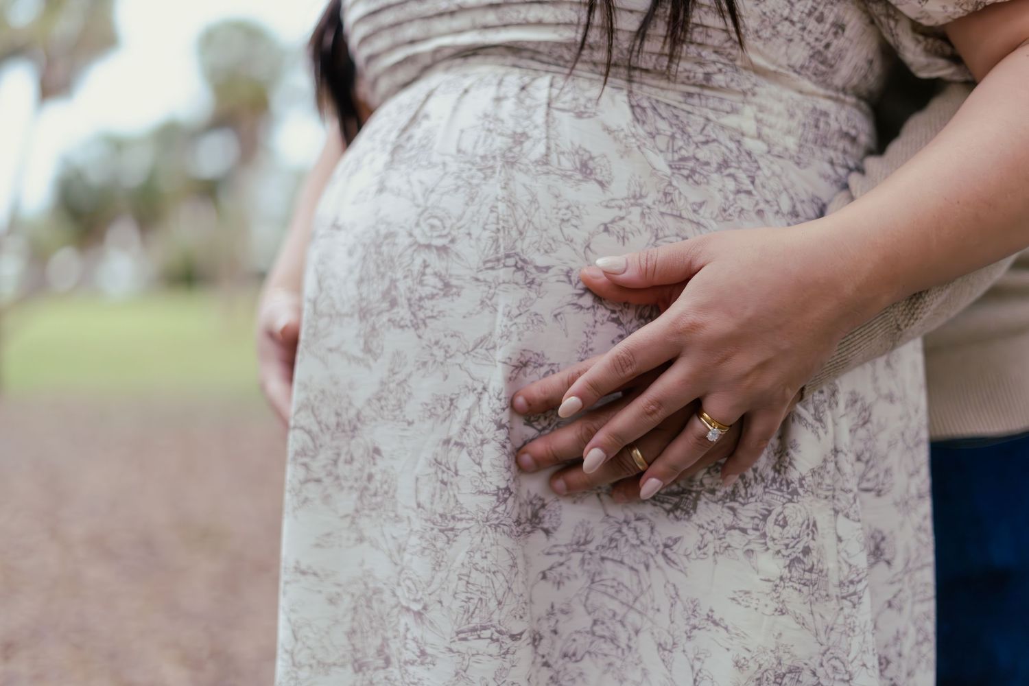 Close up view of a white lace maternity dress showing a pregnant belly.