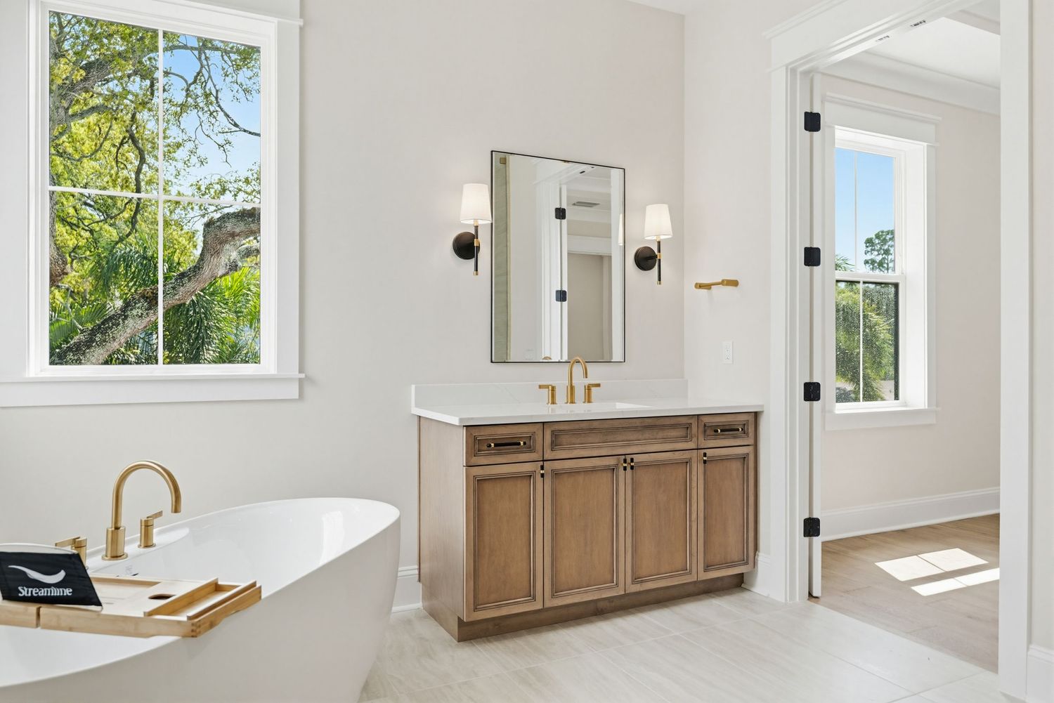 Modern bathroom interior with natural light featuring white walls, wooden vanity, and sleek fixtures.