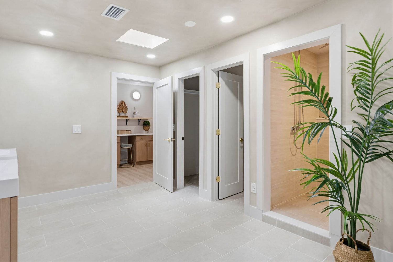 Modern medical office hallway with recessed lighting, white walls, and potted palm plants creating a professional atmosphere.