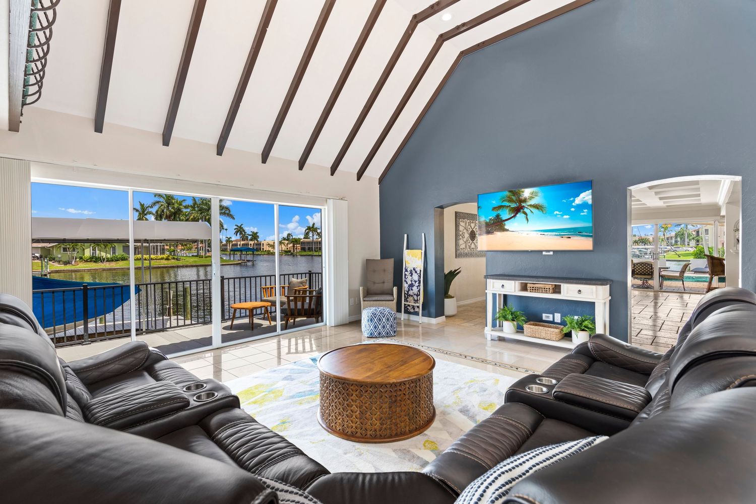 Luxurious modern home interior with glass walls, white decor, and sleek furnishings overlooking a coastal landscape.