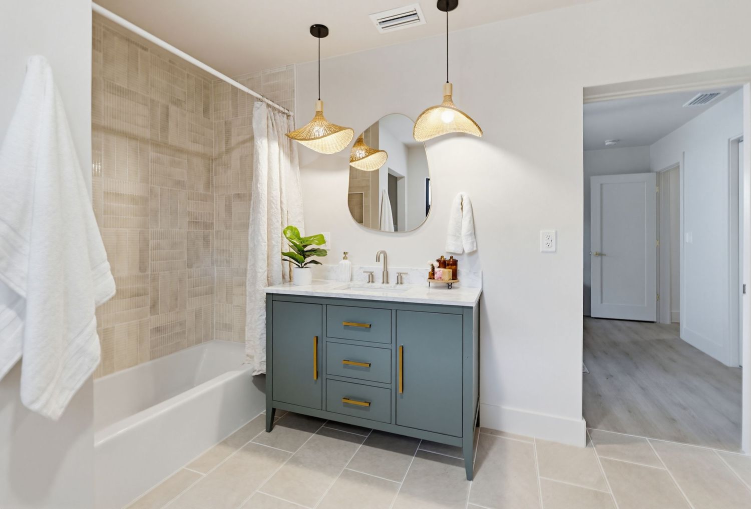 Modern bathroom interior with blue-gray vanity cabinet, white marble tile walls, and pendant lighting fixtures.