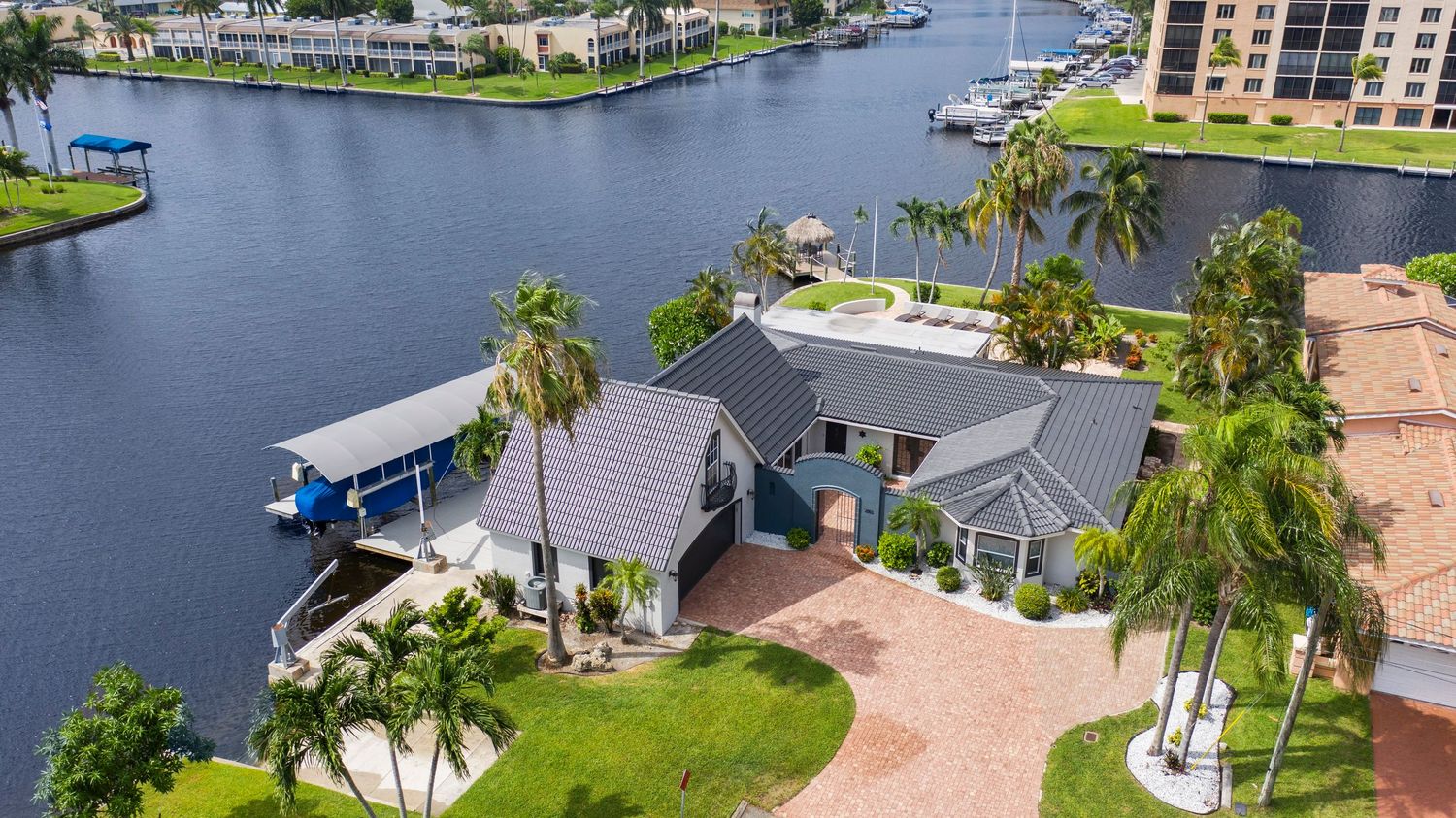 Aerial panoramic view of waterfront homes and boats docked along canals in a luxury Florida residential community.