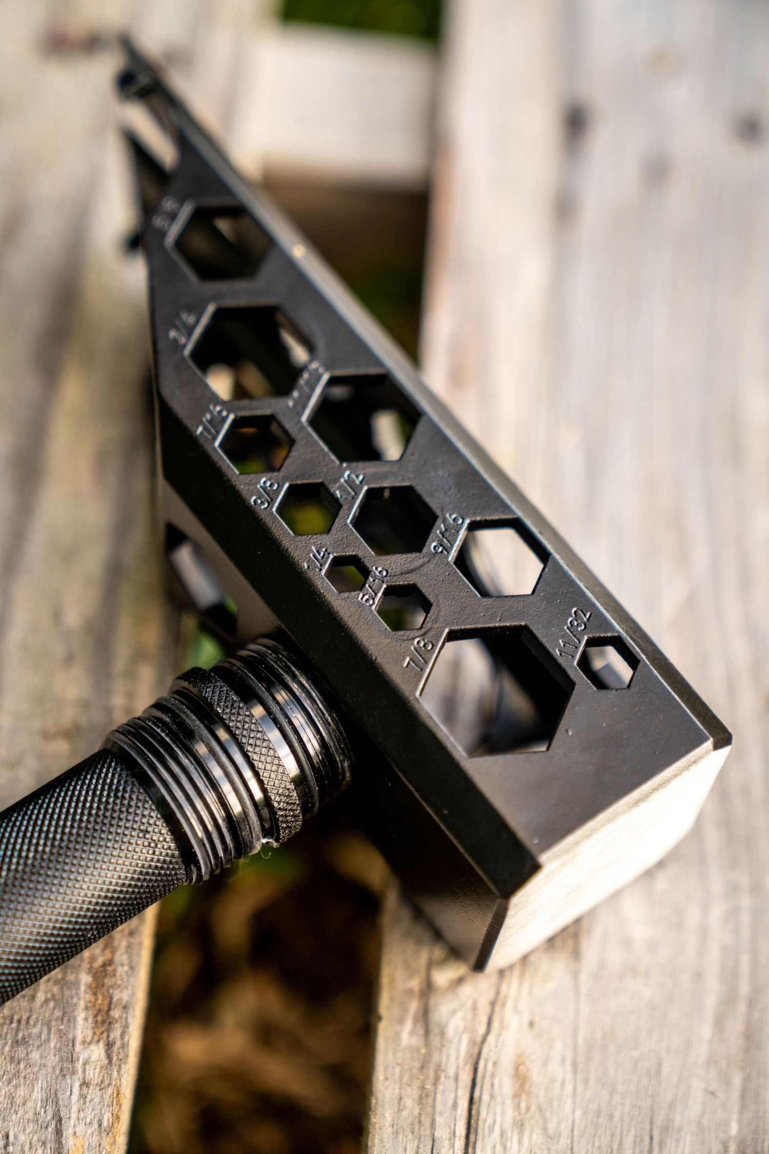 Close-up of black metal tool head with hexagonal pattern design on wooden surface.