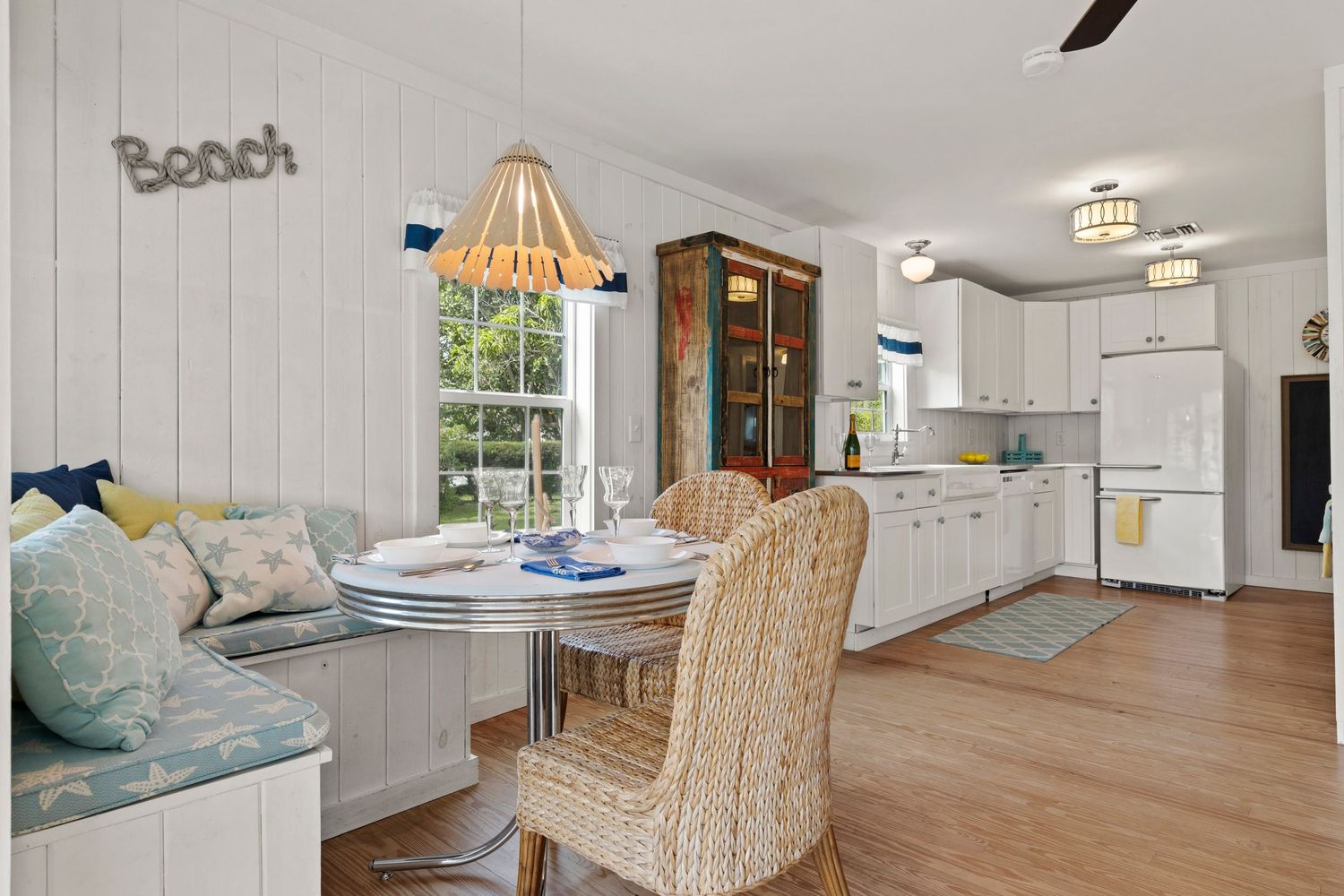 Bright coastal living space with white shiplap walls, natural rattan furniture, and beachy decor accents.