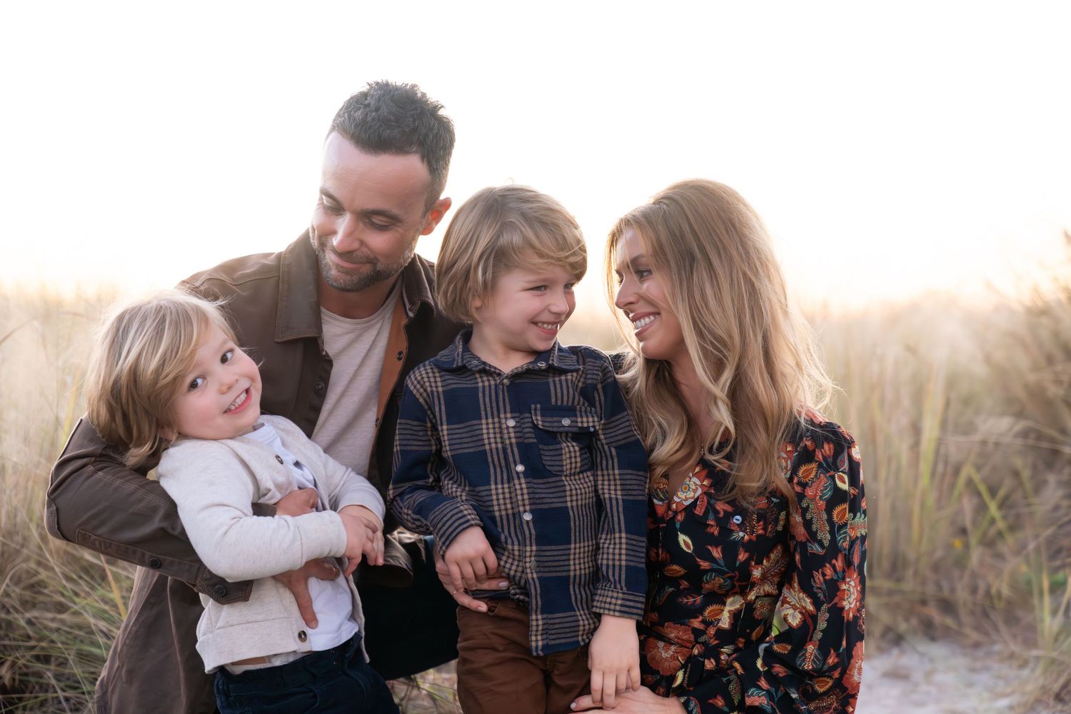 A family shares joyful moments together in a golden field during sunset.
