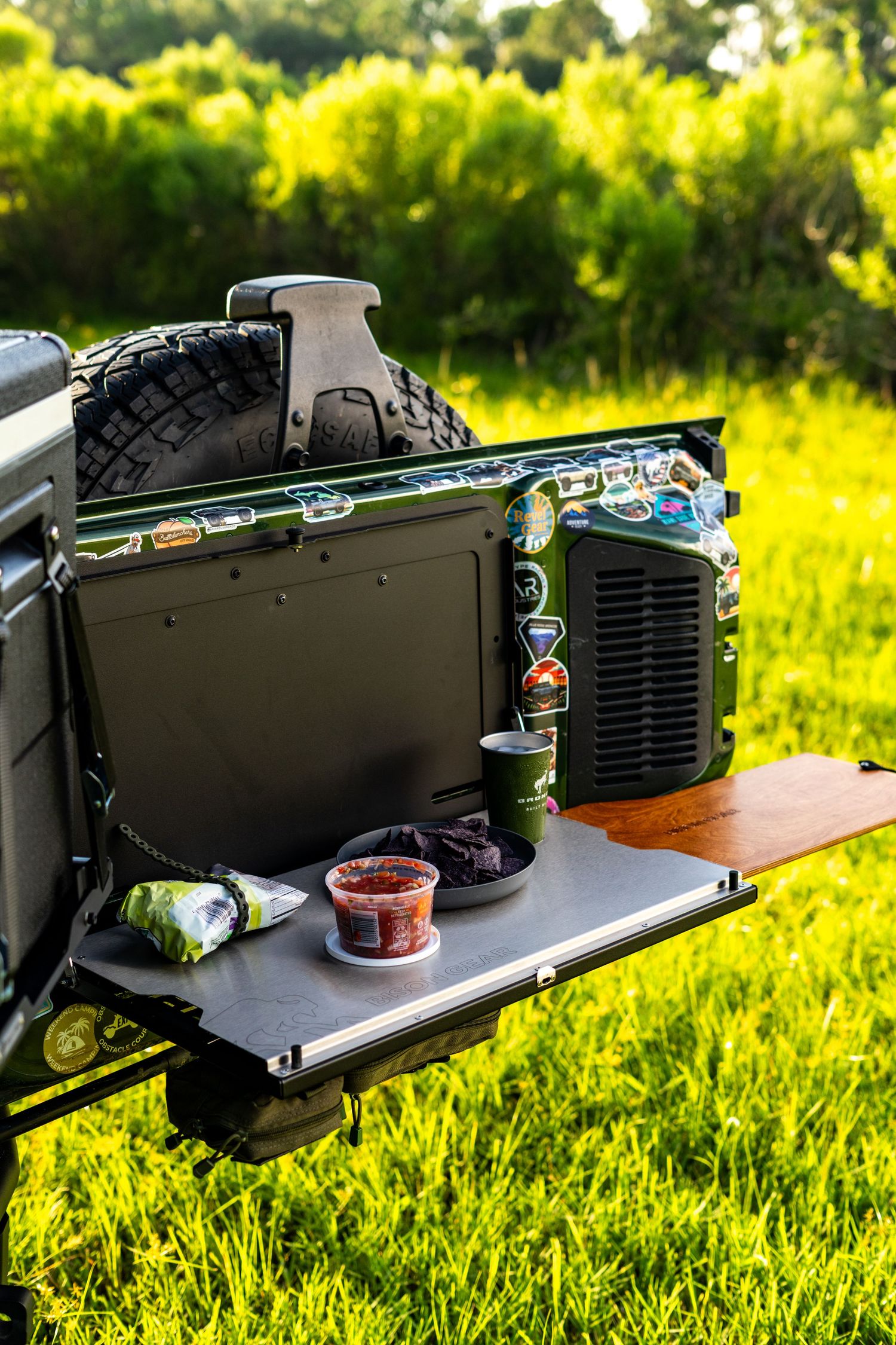 Camping gear and cooking equipment displayed on a portable table in bright sunlight.