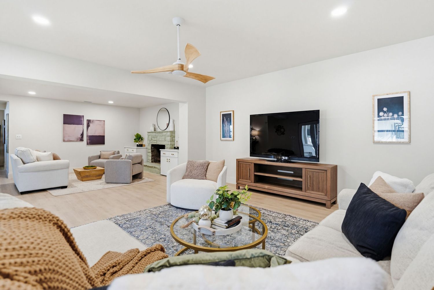 Modern basement living area with white walls, entertainment center, and comfortable seating arranged in an open concept space.