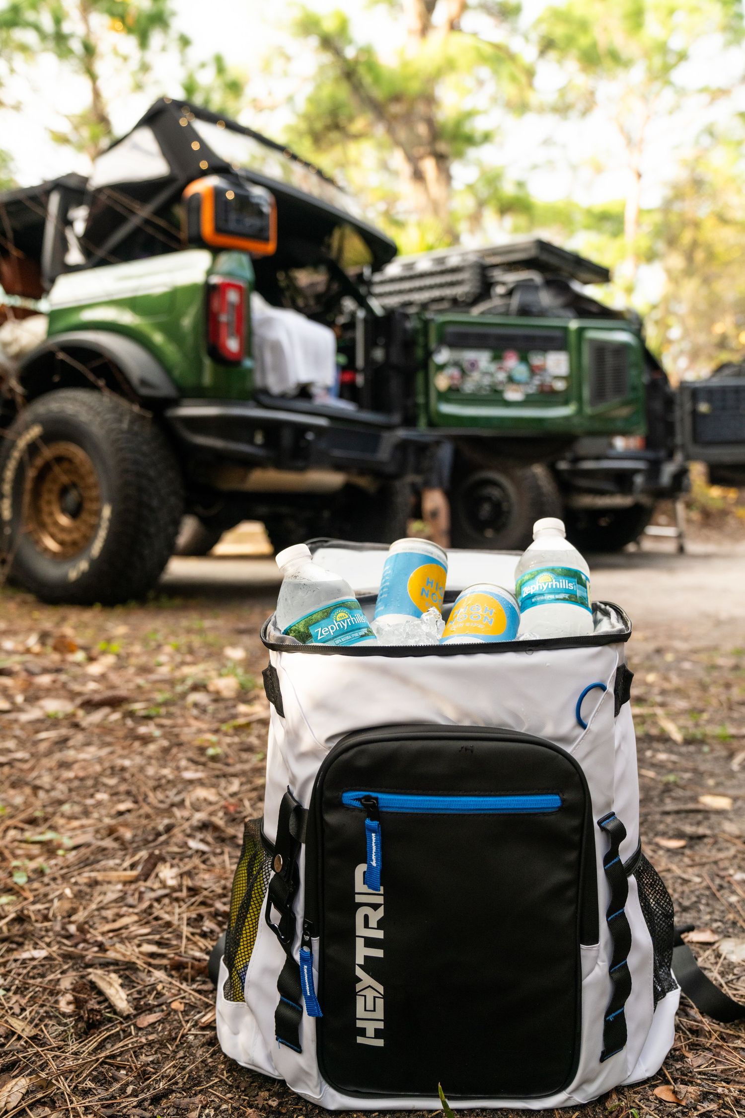 Off-road vehicle and white cooler bag with drinks on rugged outdoor terrain.