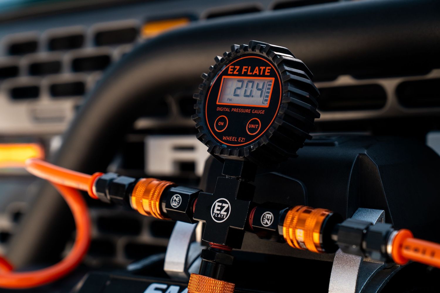 Close-up of a digital gauge mounted on handlebars with orange accents.