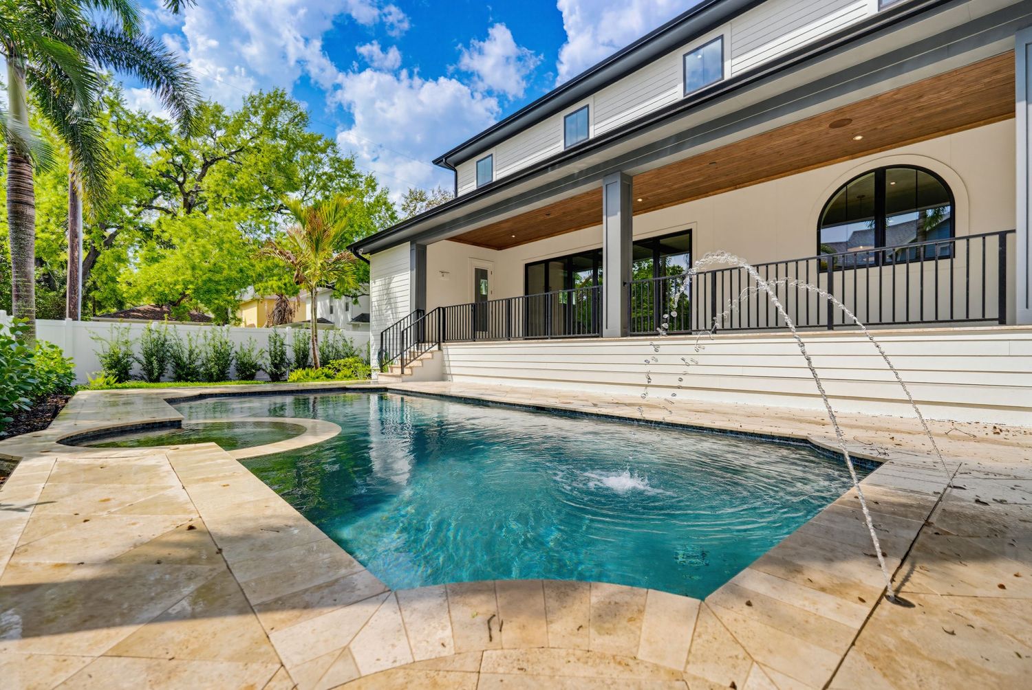 Luxurious infinity pool overlooking a tropical landscape with palm trees and blue sky in a modern backyard setting.