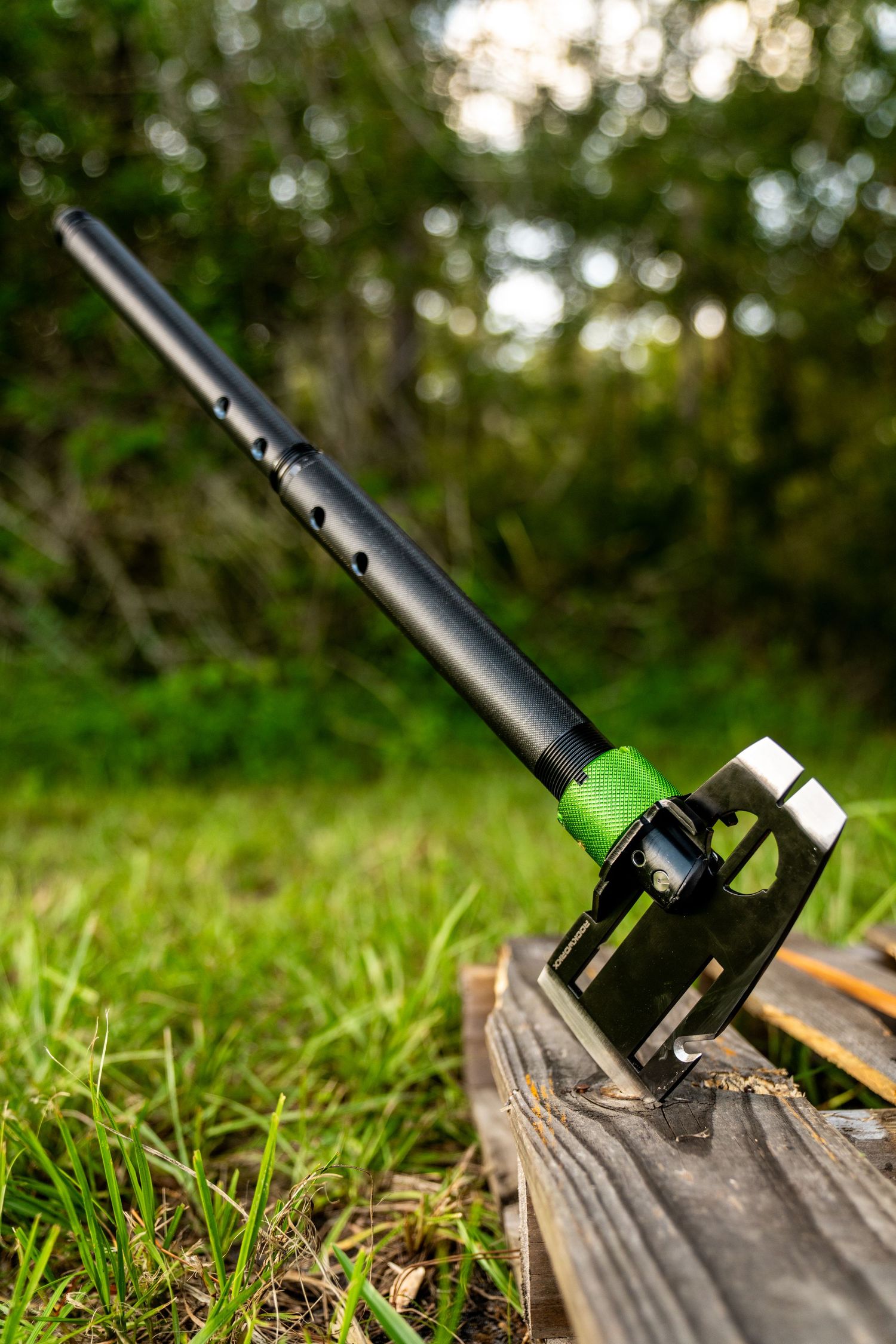 Black hi-lift jack handle mounted on weathered wood in outdoor setting.