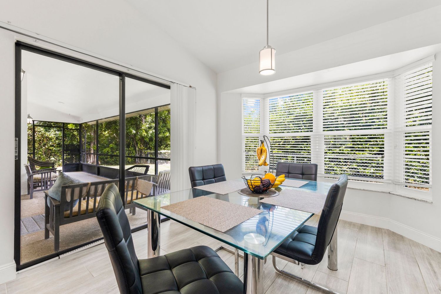 Modern open concept living room with white walls, large windows, and hardwood floors showcasing contemporary furniture.