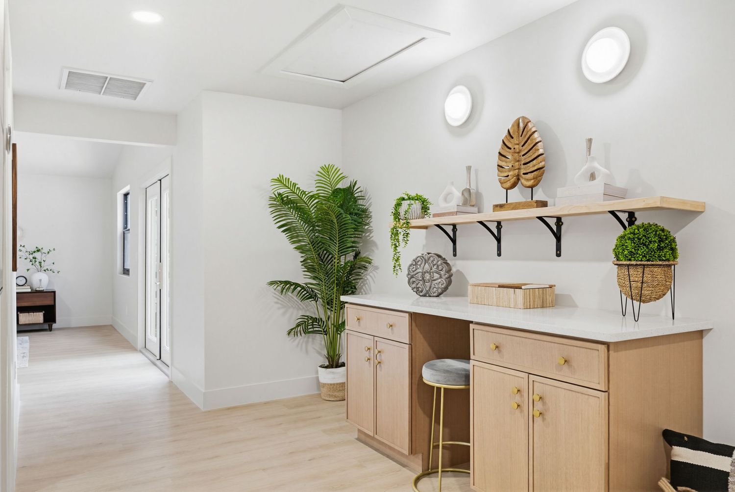 Modern white spa treatment room with wooden furniture, plants, and circular wall lights creates a serene atmosphere.