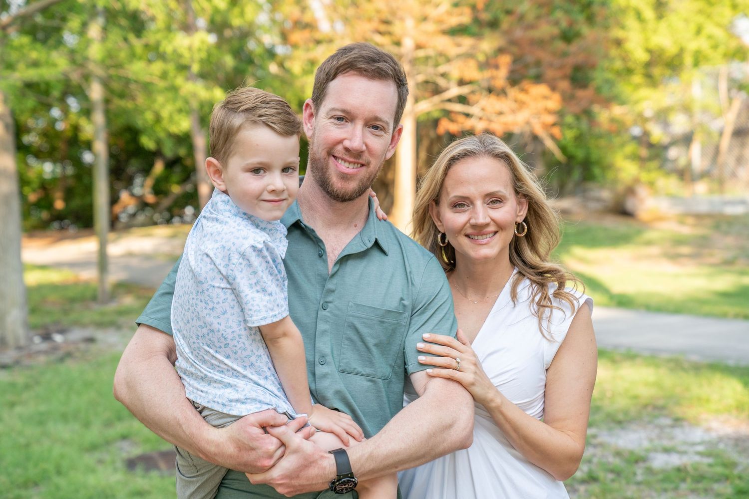 Family enjoys a candid moment together outdoors during autumn photoshoot in a park setting.
