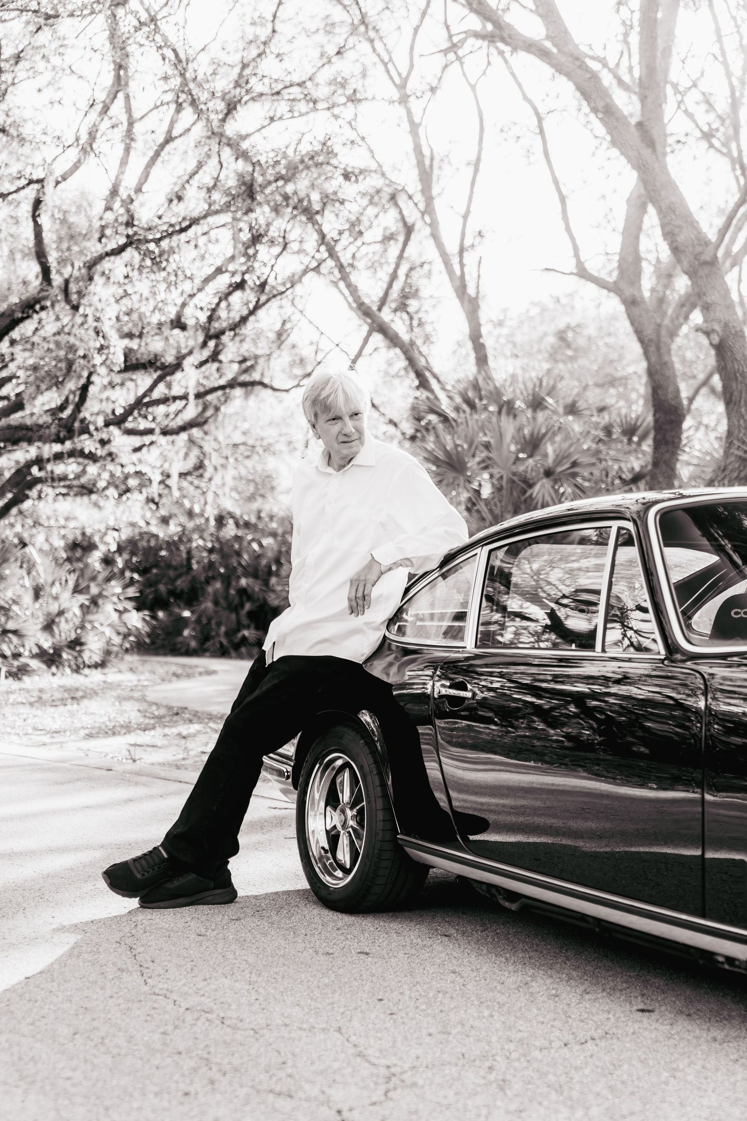 A black and white photo series showing a person lying on the ground beside a vintage car in four sequential frames.