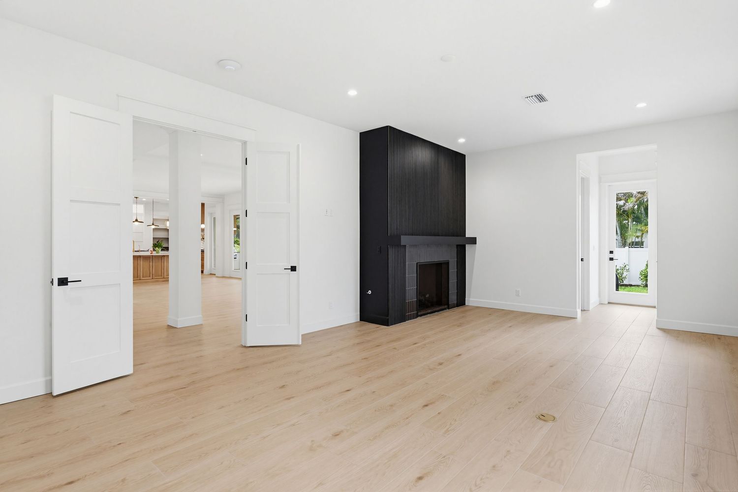 Modern open concept living space with light hardwood floors, white walls, and recessed lighting in a residential interior.