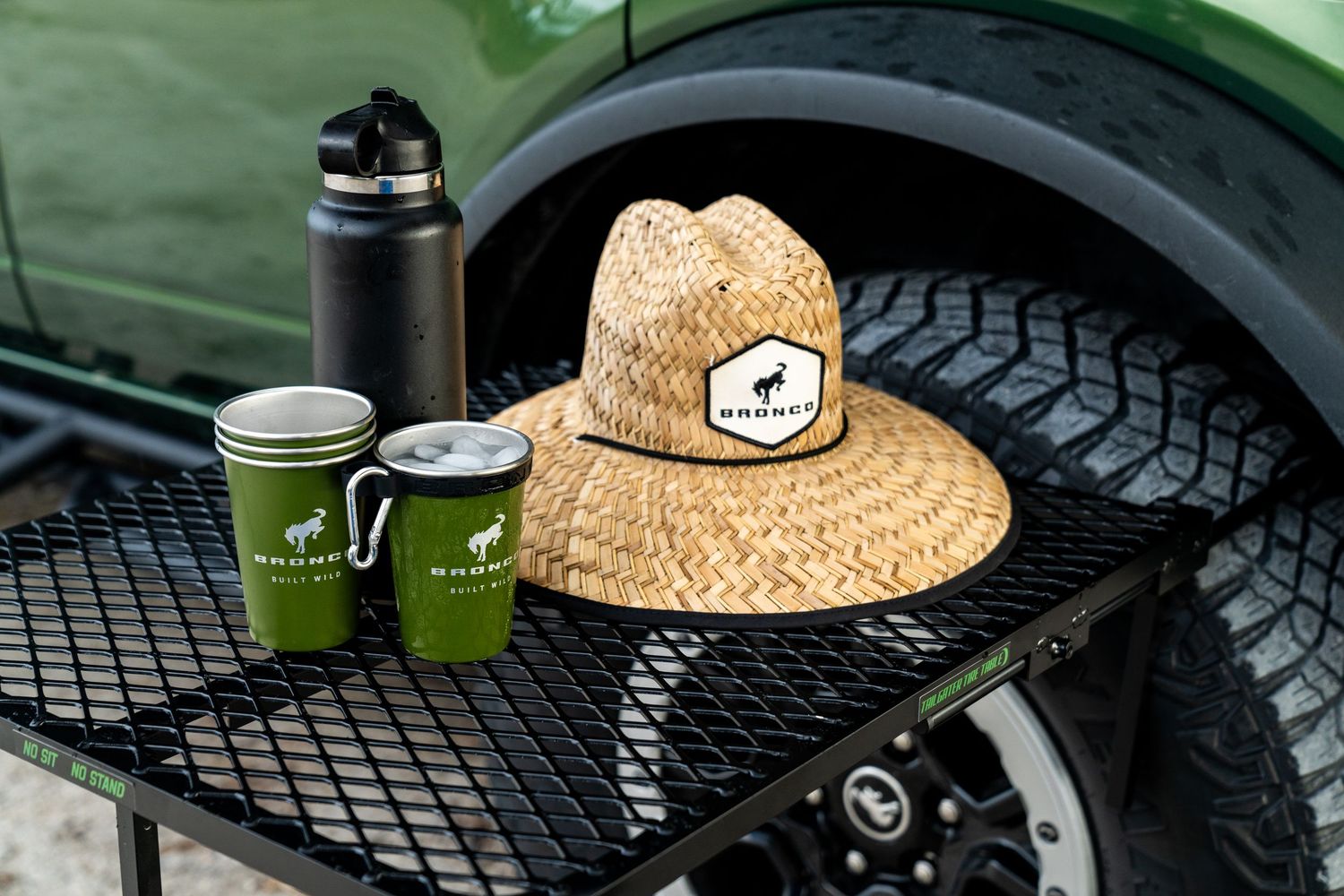 Green off-road vehicle with rugged tires and a straw hat displayed on the hood.