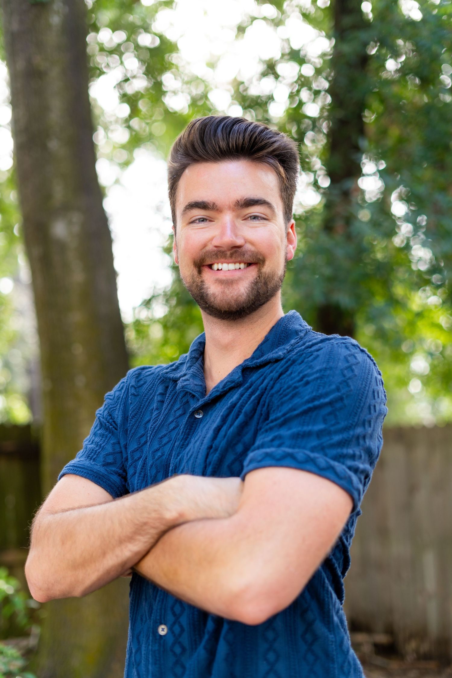 Casual outdoor portrait series showing someone in a blue button-down shirt smiling against a green forest background.