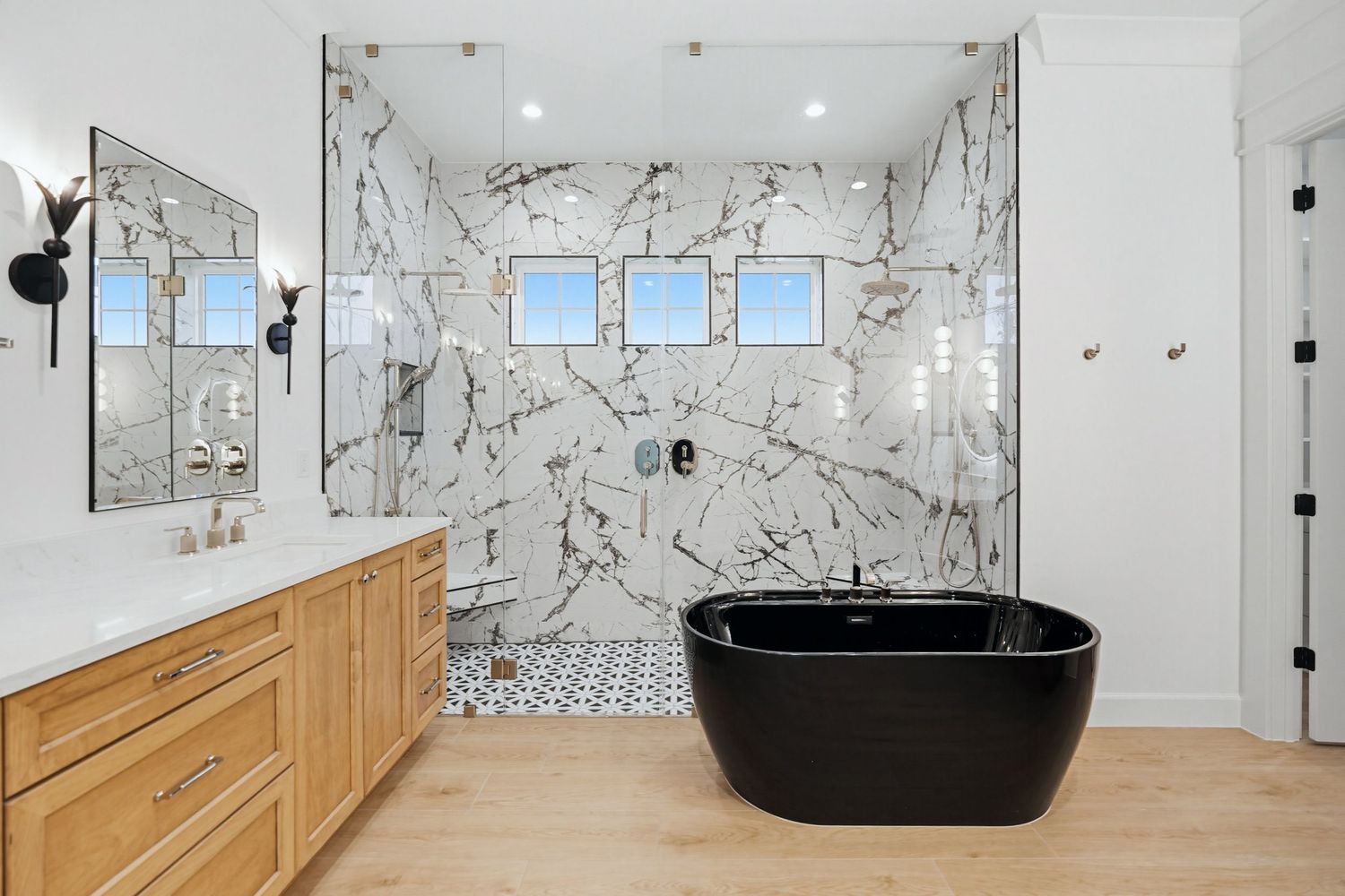 Modern bathroom with white marble walls, wooden vanity, and black vessel sink showcases sleek contemporary design.