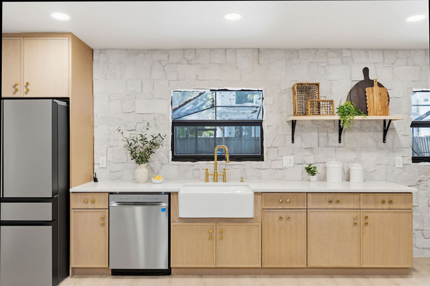Modern kitchen interior with light wood cabinets, stainless steel appliances, and white countertops in a minimalist design.