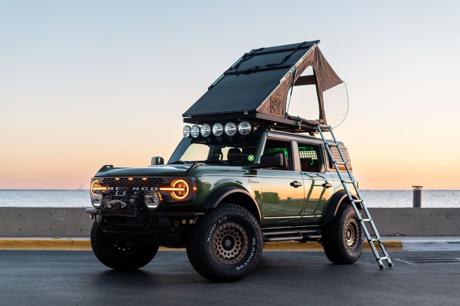 Adventure vehicle with rooftop tent photographed from side angle at sunset.
